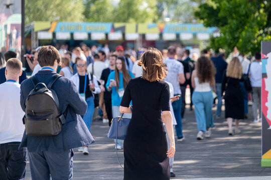 People walking and socializing in an outdoor event, exchanging ideas in a professional setting.