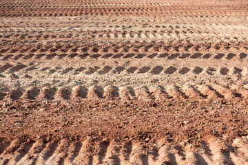 Background image showing tracks left by a tracked engineering vehicle on a dirt road surface