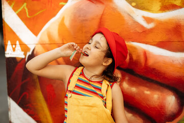 Cute little girl eating rainbow sour jelly candy strip.