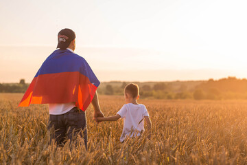 Patriotism. A father and son with the Russian flag in a wheat field at sunset. A family with a flag...