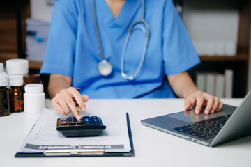 Healthcare costs and fees concept.Hand of smart doctor used a calculator and smartphone, tablet for...