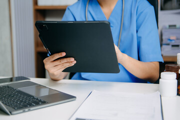 Professional nurse in blue scrubs using smartphone and laptop for medical data, prescription...