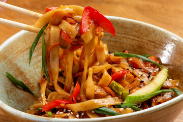 Eating noodles with vegetables with chopsticks.