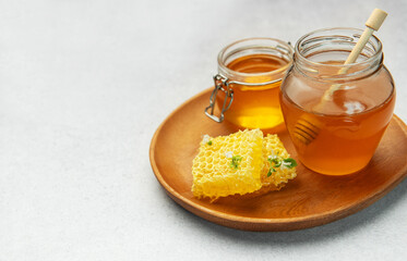 Jars and honeycombs resting on wooden tray, promoting natural sweetener and healthy lifestyle