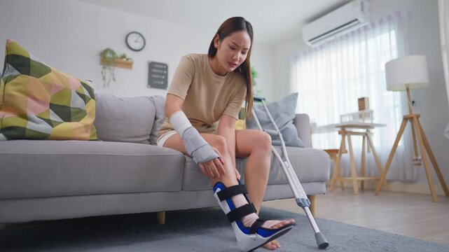 Injured Asian young woman sitting in a cozy living room at home. 