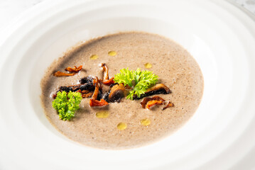 Creamy mushroom soup in a white bowl, garnished with sautéed mushrooms, parsley, and olive oil drops. Elegant presentation, ideal for culinary, restaurant, or food blog use