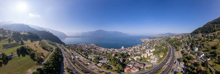 Wide angle panorama cityscape of Montreux along the Lake of Geneva in Switzerland with the French and Swiss Alps in the background and A9 freeway in the foreground