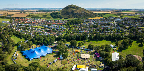 Aerial view of a vibrant festival with colorful tents and bustling crowds set against the backdrop of a lush green landscape, Haddington, Scotland, United Kingdom.