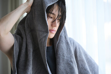 朝の窓際で入浴後のアジアの若い男性ポートレート