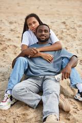 Joyful couple enjoys a romantic moment while relaxing on the sandy beach at sunset