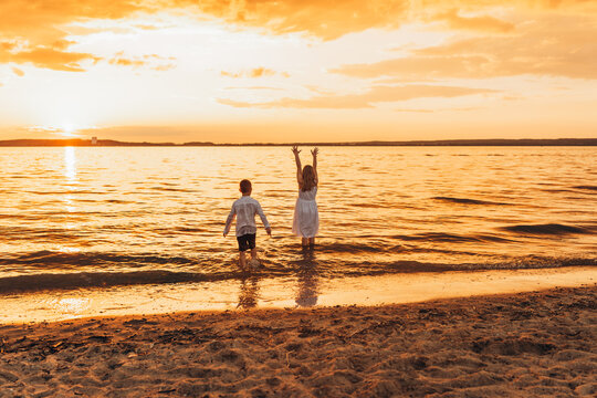 Joyful children playing in shallow water at golden sunset, sandy beach backdrop. 
 - Powered by Adobe