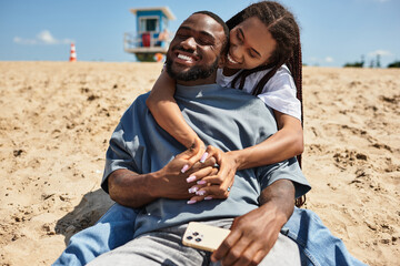 Loving couple enjoys a cheerful moment on a sandy beach under a clear blue sky