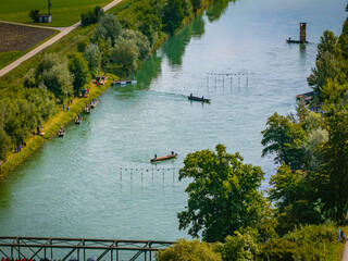 Aerial view of kayakers navigating the course on the river, amidst verdant trees and emerald waters, Augsburg, Bavaria, Germany.