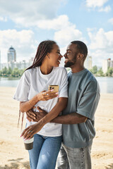 Young couple enjoys a heartfelt moment while strolling by the riverside in the city