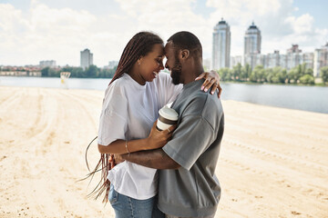 Young couple in love share a cozy moment by the waterfront during a sunny afternoon stroll