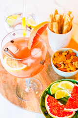Gin and tonic and grapefruit juice cocktails, with wodka grapeftuir and lime, snacks on table, nuts, breadsticks, drinking cocktails with friends