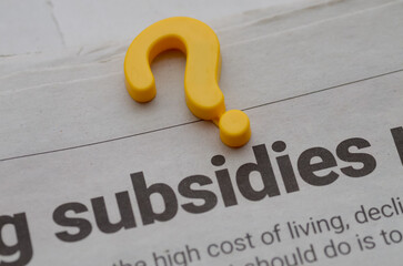 Question Mark on “Subsidies” Newspaper Headline — Policy Uncertainty and Economic Debate Concept