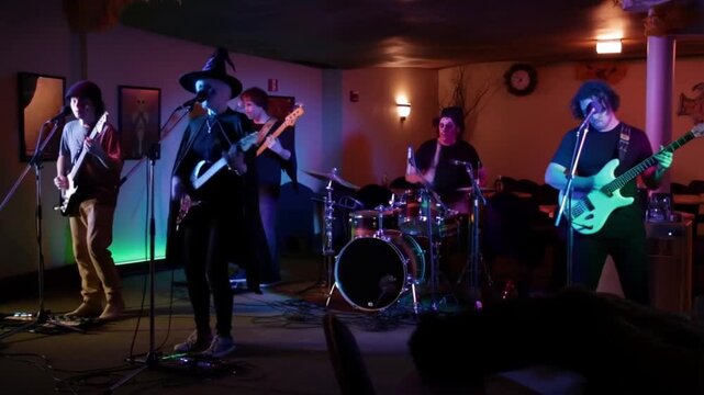 Live musicians in halloween costumes playing on restaurant stage, camera moves along stage, neon light. Concept of festive halloween restaurant entertainment