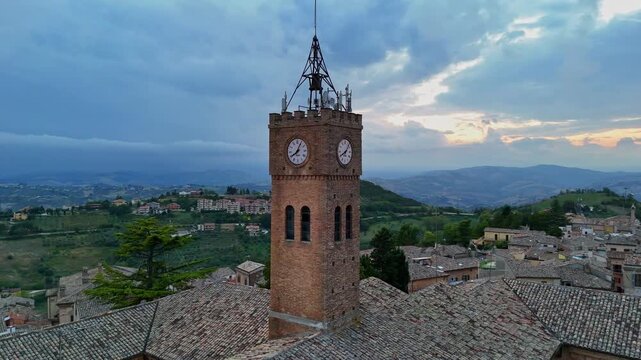 Drone orbit shot of the historic clock tower in Atri old town at sunset, Italy