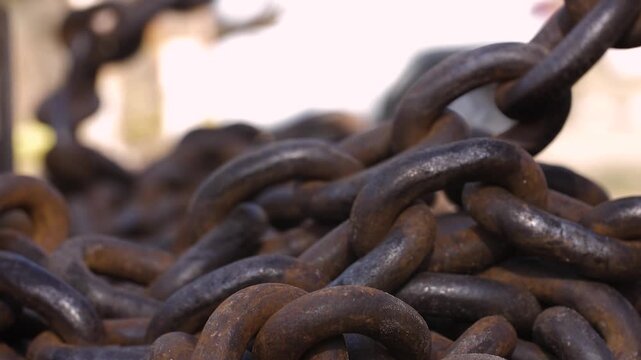 Close-up slow motion footage of heavy rusty iron chains with detailed texture and weathered metal links in industrial setting
