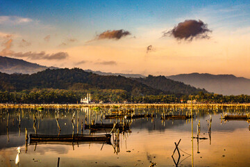 Mountain view with mosques and lakes with fish cages in the foreground, beautiful blue sky in the background