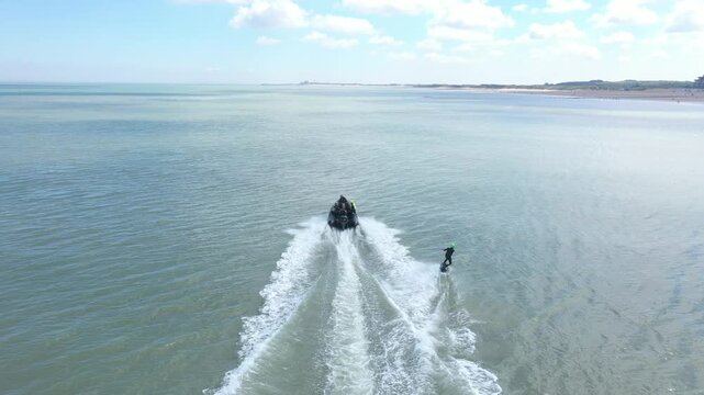Aerial view of a person wakeboarding behind boat in a beautiful sea, emitting a sense of freedom, Knokke, Flanders, Belgium.
