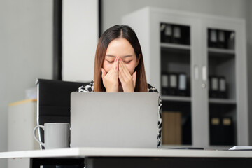 Tired asian businesswoman with headache at office, feeling sick at work.