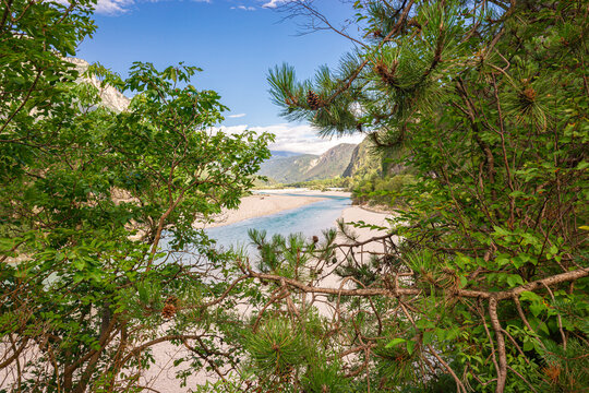 Serene river landscape of Fiume Fella river in northeast Italy framed by lush green foliage and mountain scenery