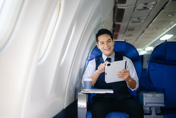 Young businessman working on a tablet while enjoying coffee in first class. Perfect image for...