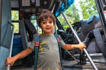 Preschooler entering school bus holding handrail, back to school