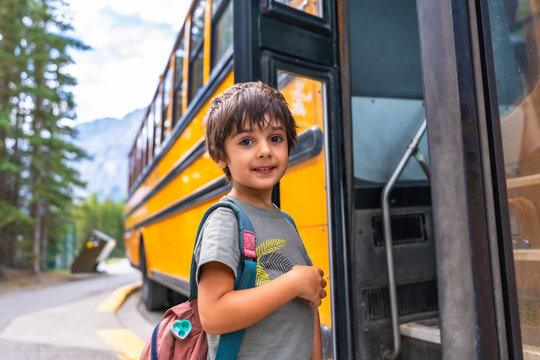Happy pupil getting on the school bus for his first day of class