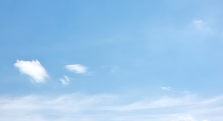 A serene and tranquil pale blue sky with a few wispy, soft white clouds. The minimalist composition...