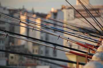 Dozens of fishing rods extend outward in perfect alignment from the Galata Bridge in Istanbul,...