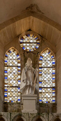 Langrune-Sur-Mer, France - 08 05 2025: Detail view of a statue and stained glass windows inside the Saint-Martin Church