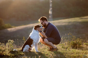 Man in nature with his dog, showing affection.