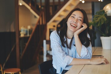 Portrait Cheerful Asian woman smiling at modern cafe, representing freelance lifestyle, digital...