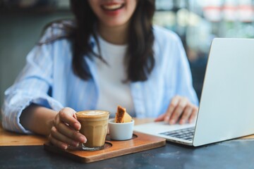 Close up Asian woman hands holding a cup of hot coffee at modern cafe, representing freelance...