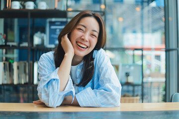 Portrait Cheerful Asian woman smiling at modern cafe, representing freelance lifestyle, digital...