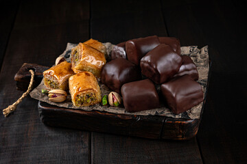 Baklava in chocolate glaze on craft paper and wooden boards. Healthy sweets, natural desserts, sugar free treats, clean eating concept.