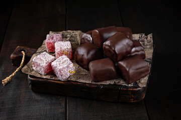 Turkish delight in chocolate glaze on craft paper and wooden boards. Healthy sweets, natural desserts, sugar free treats, clean eating concept.