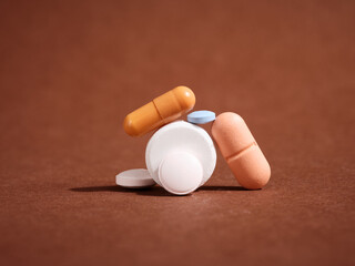 Colorful pills and capsules forming an unstable structure on brown background