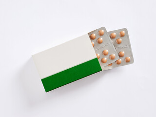 Green and white medicine box revealing blister packs of pills
