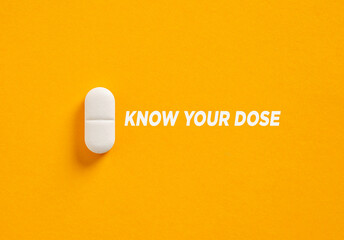 White Pill and Know Your Dose Sign on Orange Background