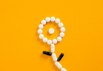 White and green pills forming a flower on orange background