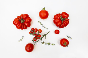 Assorted fresh heirloom, oxheart, cherry tomatoes. Arranged red vegetable varieties, thyme herb isolated on white background. Organic food, healthy eating, harvest. Gardening. Flat lay, top view
