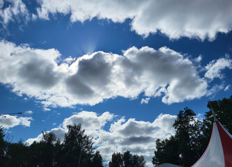 Obraz premium On a blue sky on a summer day, gray clouds in the shape of a hippopotamus with a crown of rays from the bright sun