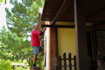 Elderly man in his late sixties repairing his home.