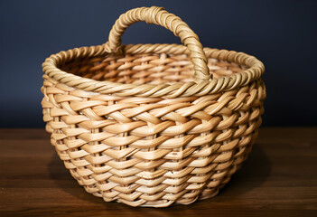 Obraz premium Woven basket with handle on wooden surface.
