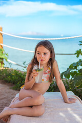 A candid beach moment showing a girl cooling off with a refreshing minty nonalcoholic mojito,...