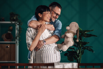 Loving couple embracing and showing teddy bear to their unborn baby